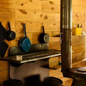 Kitchen area with cast iron skillets, silverware, and a wood burning stove. You can also cook outside over a fire if that's more your style.