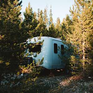 the camper is tucked away in the woods, surrounding by trees