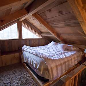 Cozy lofted nook, with nothing but trees and sky out the window.