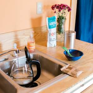 The kitchen is well-stocked with a kettle, stovetop, pots, coffee maker, microwave, fridge and more.