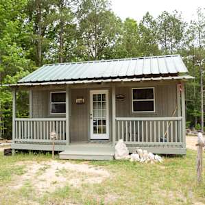 Tiny cabin, set in front of the trees.