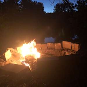 The large fire pit at night in front of the lake.