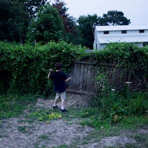 Small child found engaged in fun on farm with no toys, no screens, nothing but dirt and a fence.