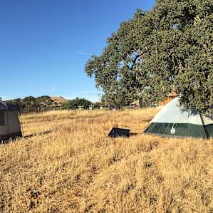 Our solar shower tent, solar panel, and bedroom at Pioneer Home Farms.