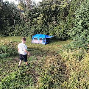 Private campsite down a hill and next to the woods.