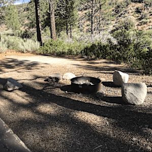 Tent site, fire pit, and picnic bench at the camp site
