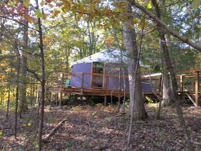 Purple yurt on wooden deck surrounded by colorful autumn forest
