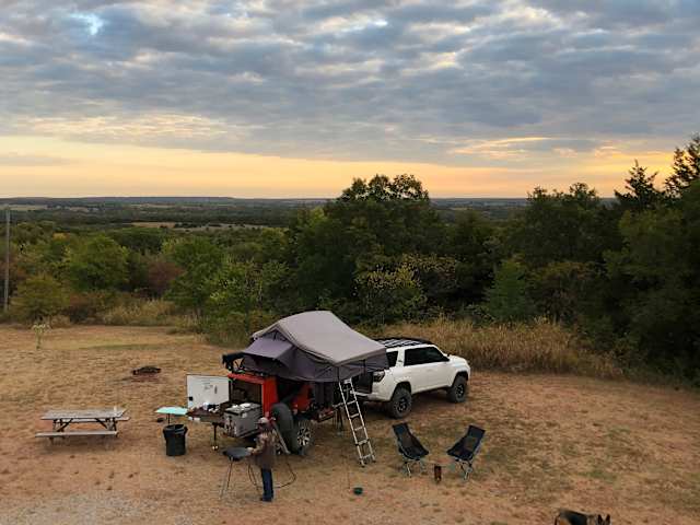 Rooftop tent camp on hilltop overlook at sunset with rolling wooded valley below