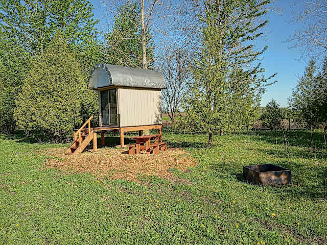 Wooden slide dock beside pond at sunset with farm fields and horses beyond