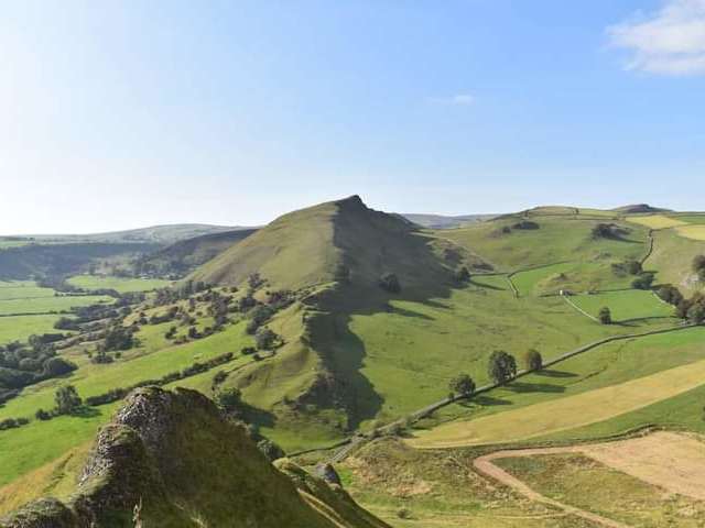 Dramatic green ridge of Chrome Hill rising above rolling Peak District countryside