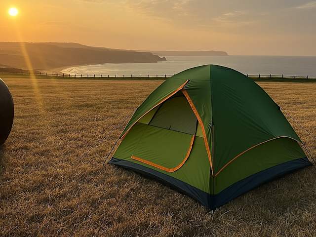 Green dome tent on grassy clifftop at sunset overlooking Scarborough Bay coastline