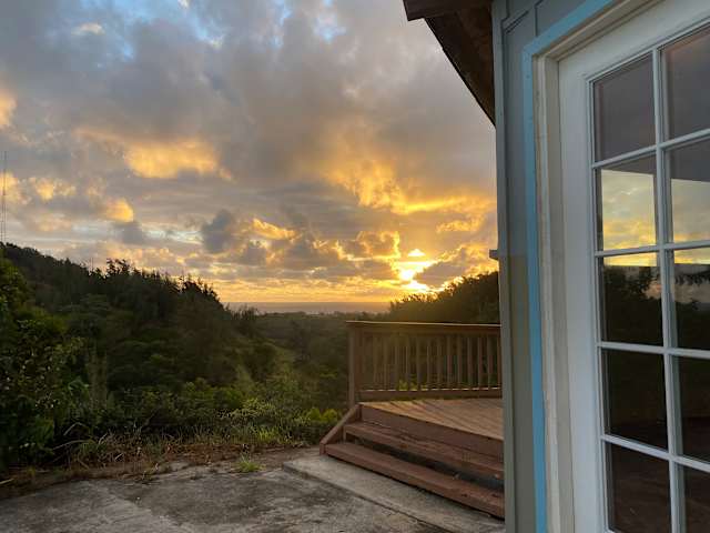 Deck and doorway overlooking lush valley under glowing sunset clouds