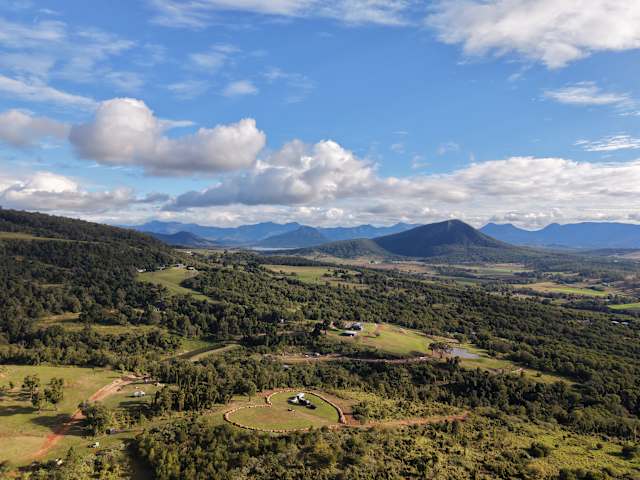 Aerial view of rolling hills and valley farmland glowing at golden hour, mountains in distance